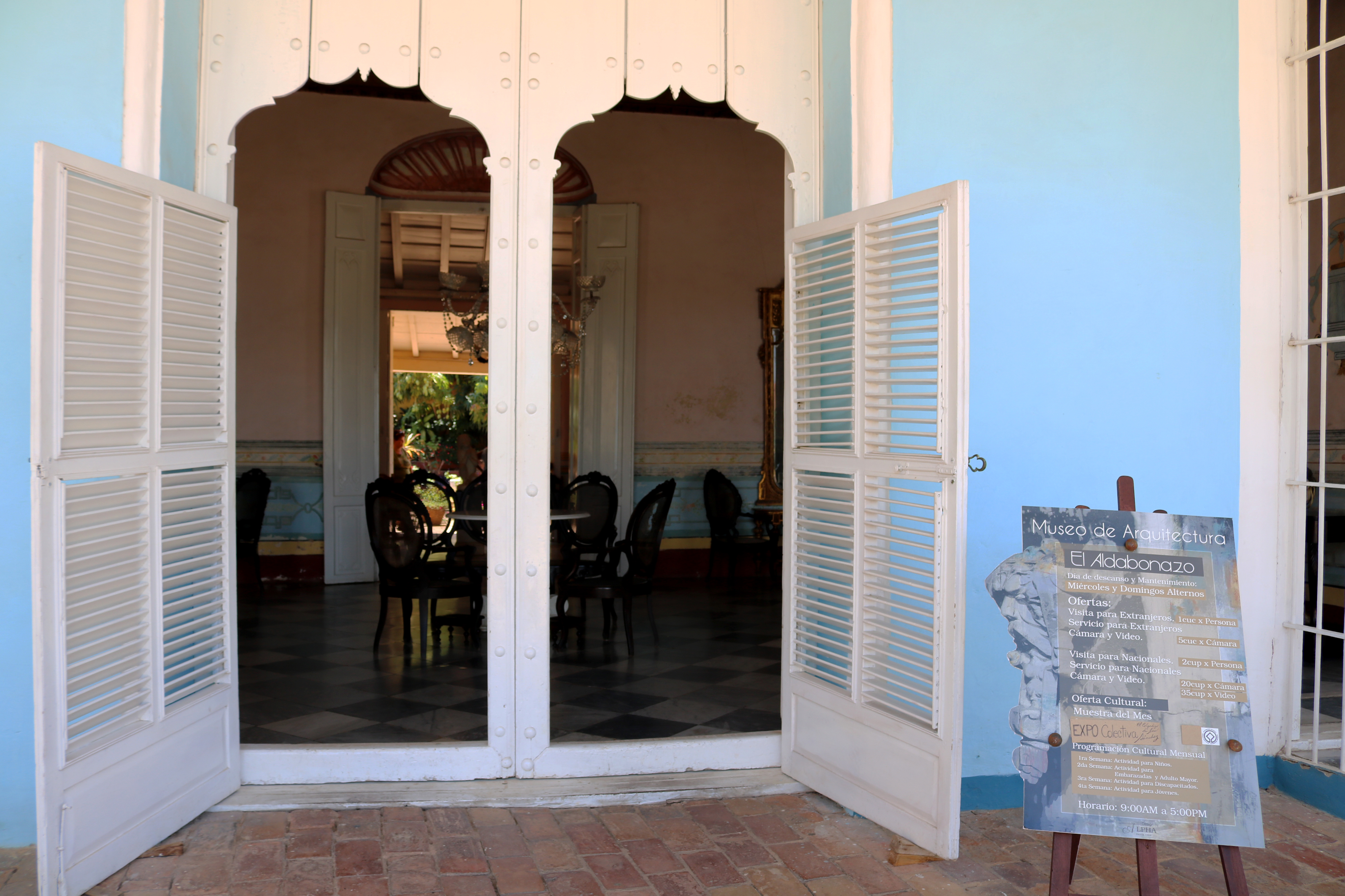 A colonial doorway and courtyard entrance at Plaza Mayor in Trinidad, Cuba, with weathered stone steps and ironwork.