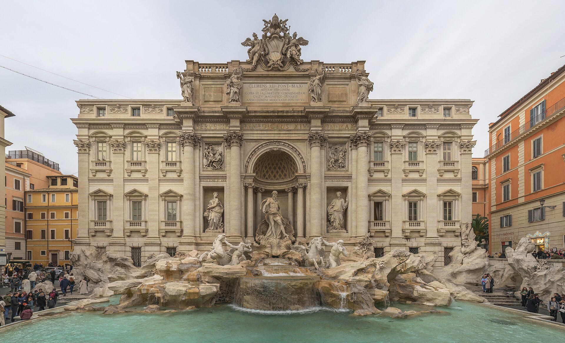The Trevi Fountain in Rome, its sculpted figures and rock formations rising above the water in front of the palace facade.