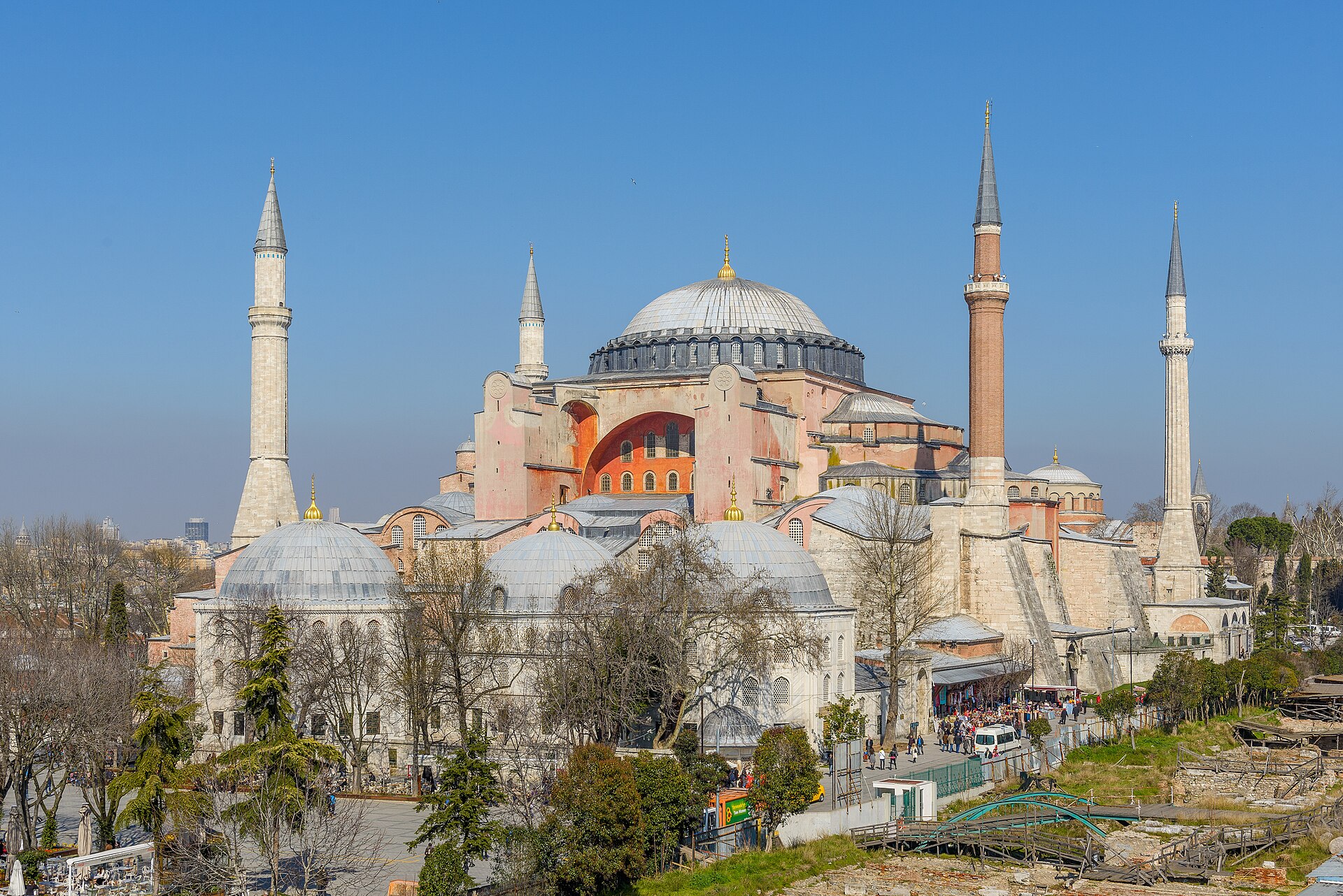 The exterior of Hagia Sophia in Istanbul, its great central dome flanked by half domes and four minarets, seen across the surrounding plaza.