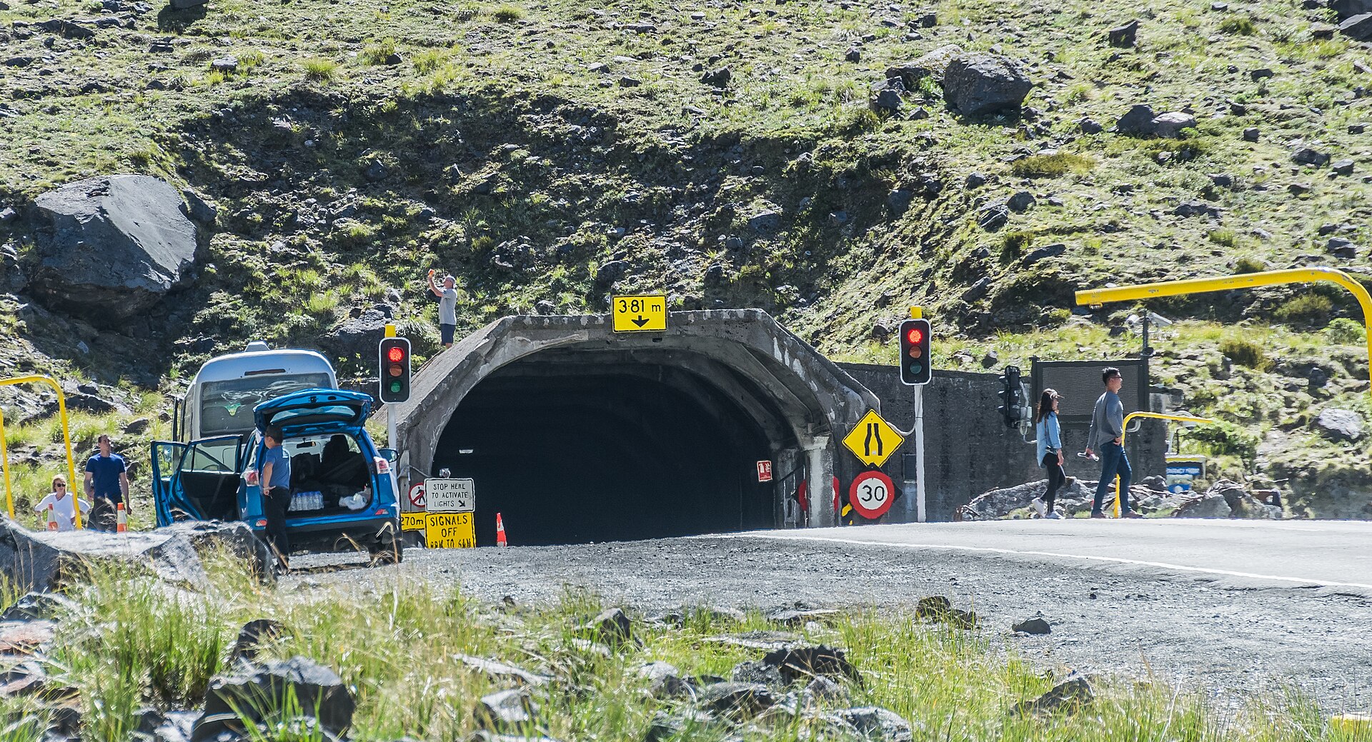 The eastern portal of the Homer Tunnel cut into a sheer rock face in Fiordland National Park, New Zealand, with snow on the surrounding peaks.