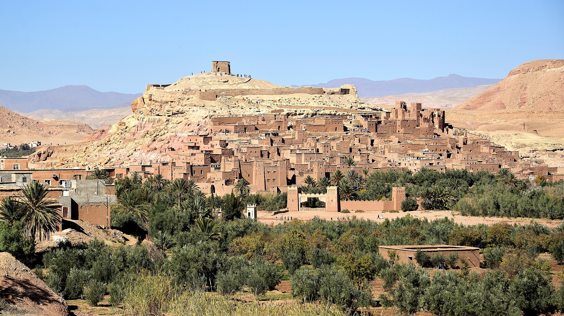 The mud brick kasbah of Ait Benhaddou in southern Morocco rising in tiers up a hillside above the valley floor.
