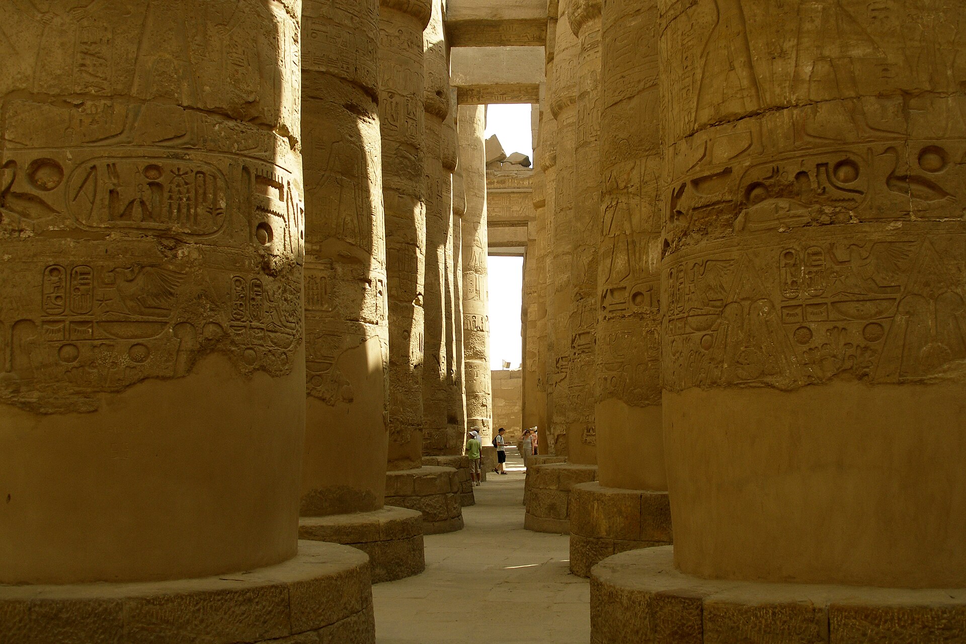The Great Hypostyle Hall at Karnak in Luxor, rows of massive stone columns covered in carved reliefs receding into shadow.
