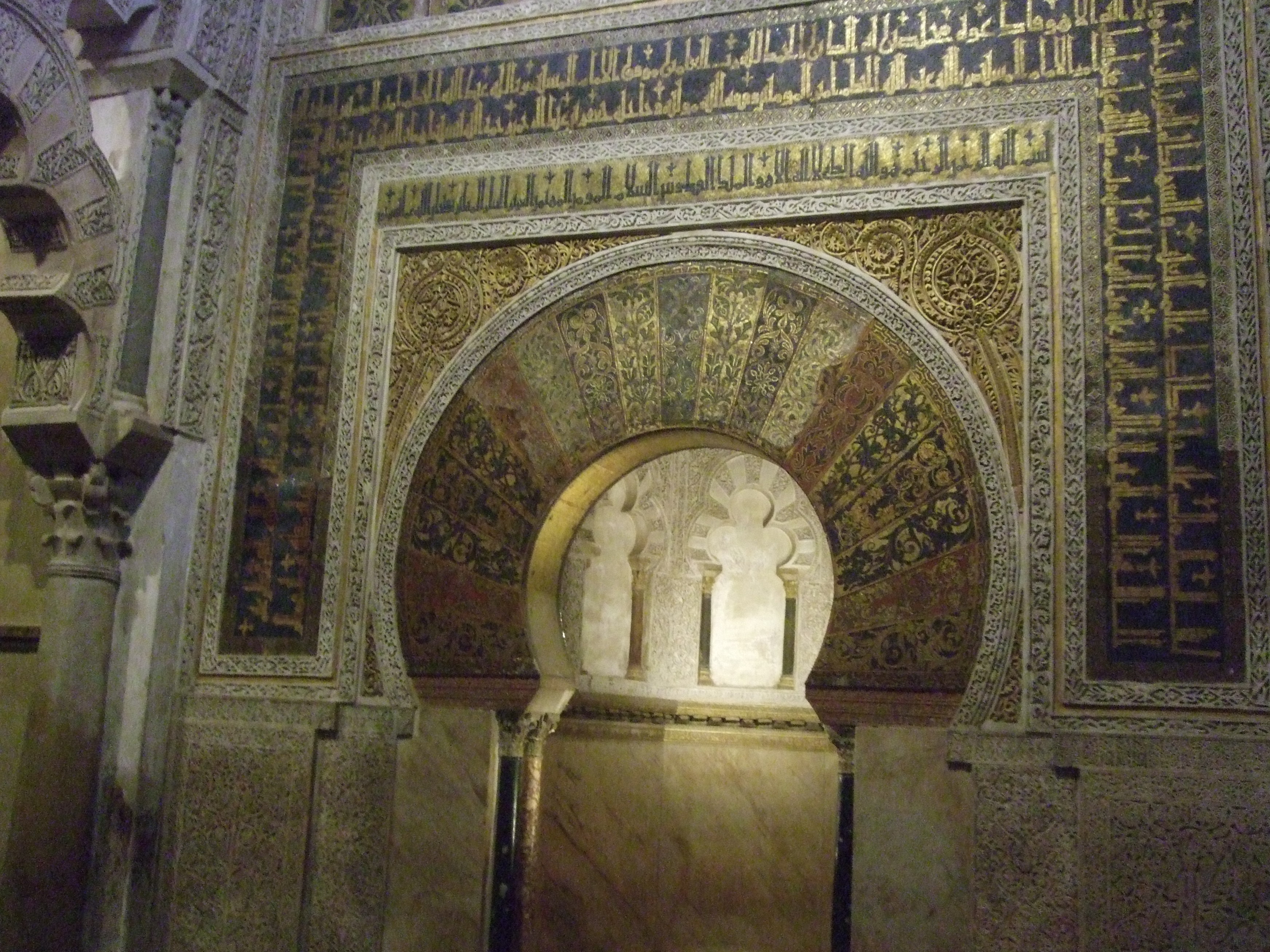Rows of red and white striped double arches inside the Mezquita-Catedral in Córdoba, receding into the dim interior of the former mosque.