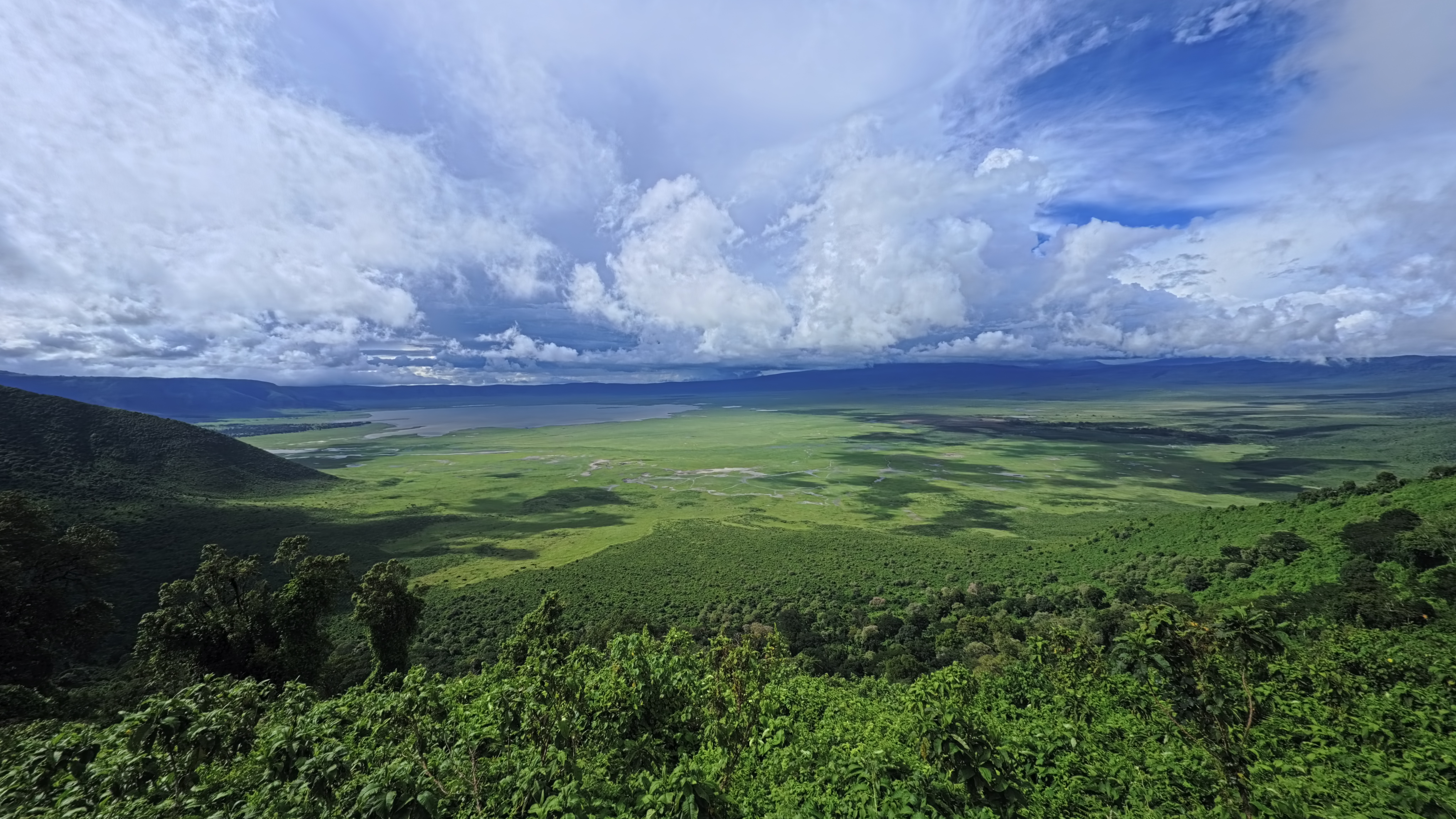 A wide view down into the Ngorongoro Crater, its floor and far walls visible under an open sky.