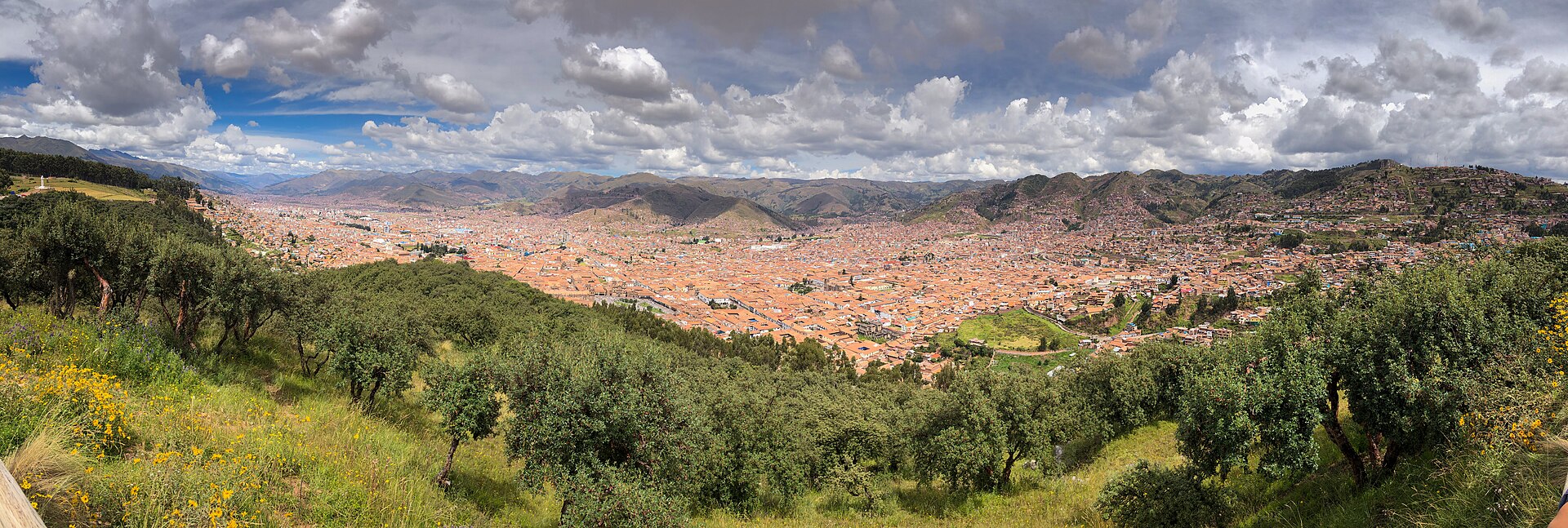 A wide view over the city of Cusco in Peru, its tiled roofs filling a bowl in the Andes with bare hills rising on all sides.