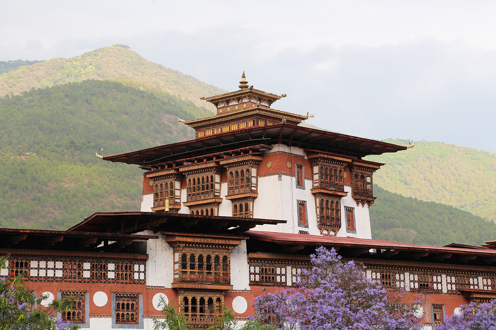Punakha Dzong beside its river, a white-walled fortress with red-trimmed roofs and a golden finial.