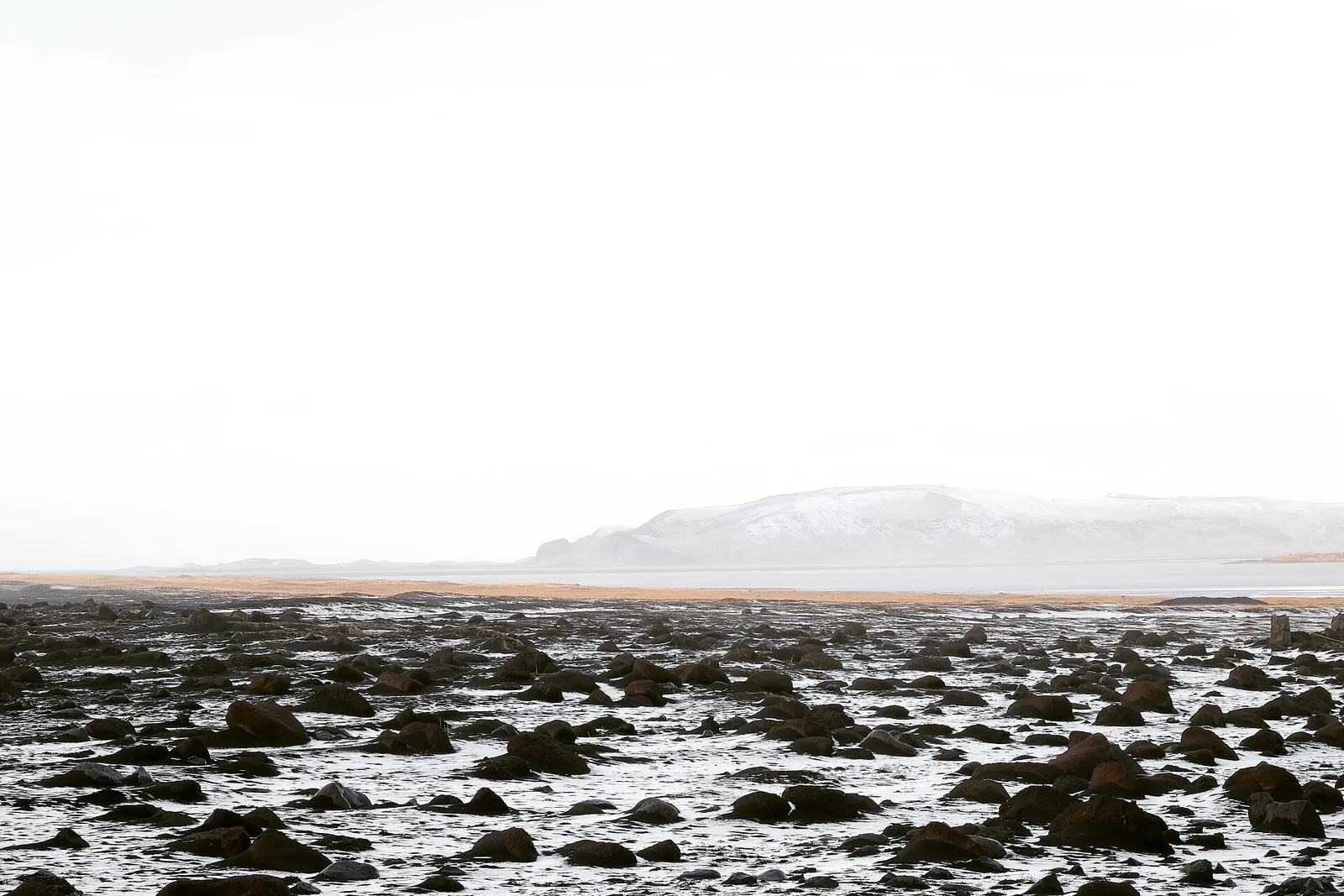 The black sand beach at Reynisfjara in Iceland with waves washing up the shore and sea stacks in the distance.
