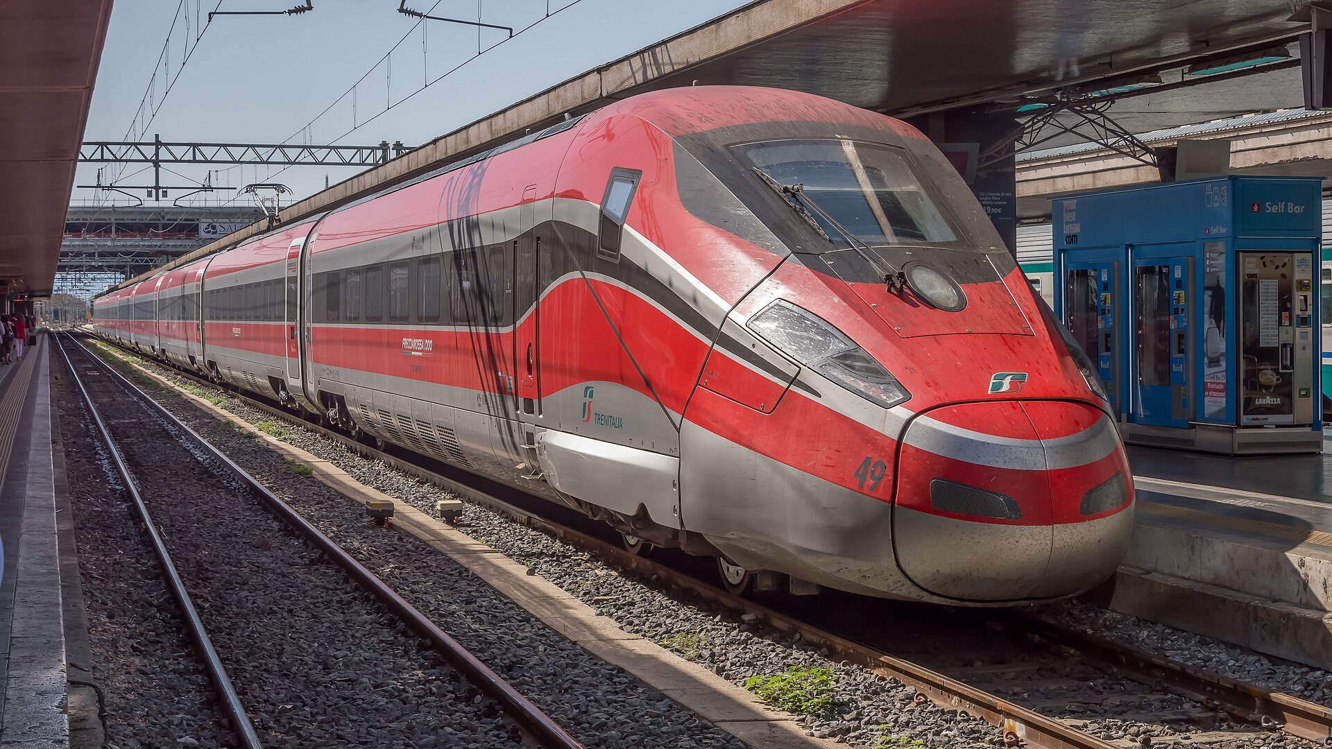 A red and grey Frecciarossa 1000 high speed train waiting at a platform at Rome Termini station.