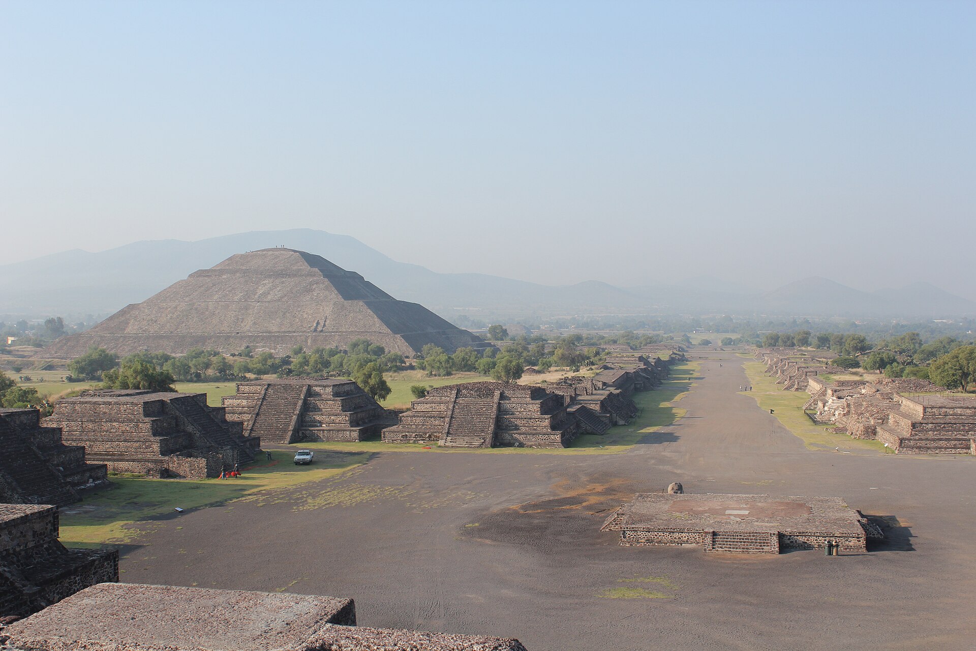 The Pyramid of the Sun at Teotihuacan seen from above, with the Avenue of the Dead running away from it between low ruined platforms.