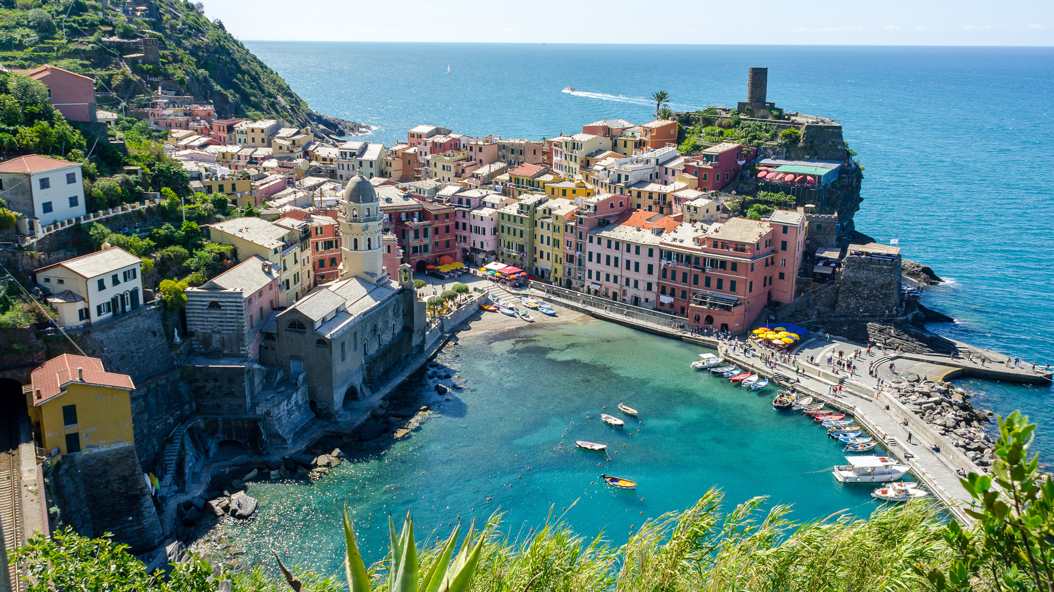 A panoramic view of Vernazza's harbour and pastel houses stacked above the water in the Cinque Terre, Liguria.