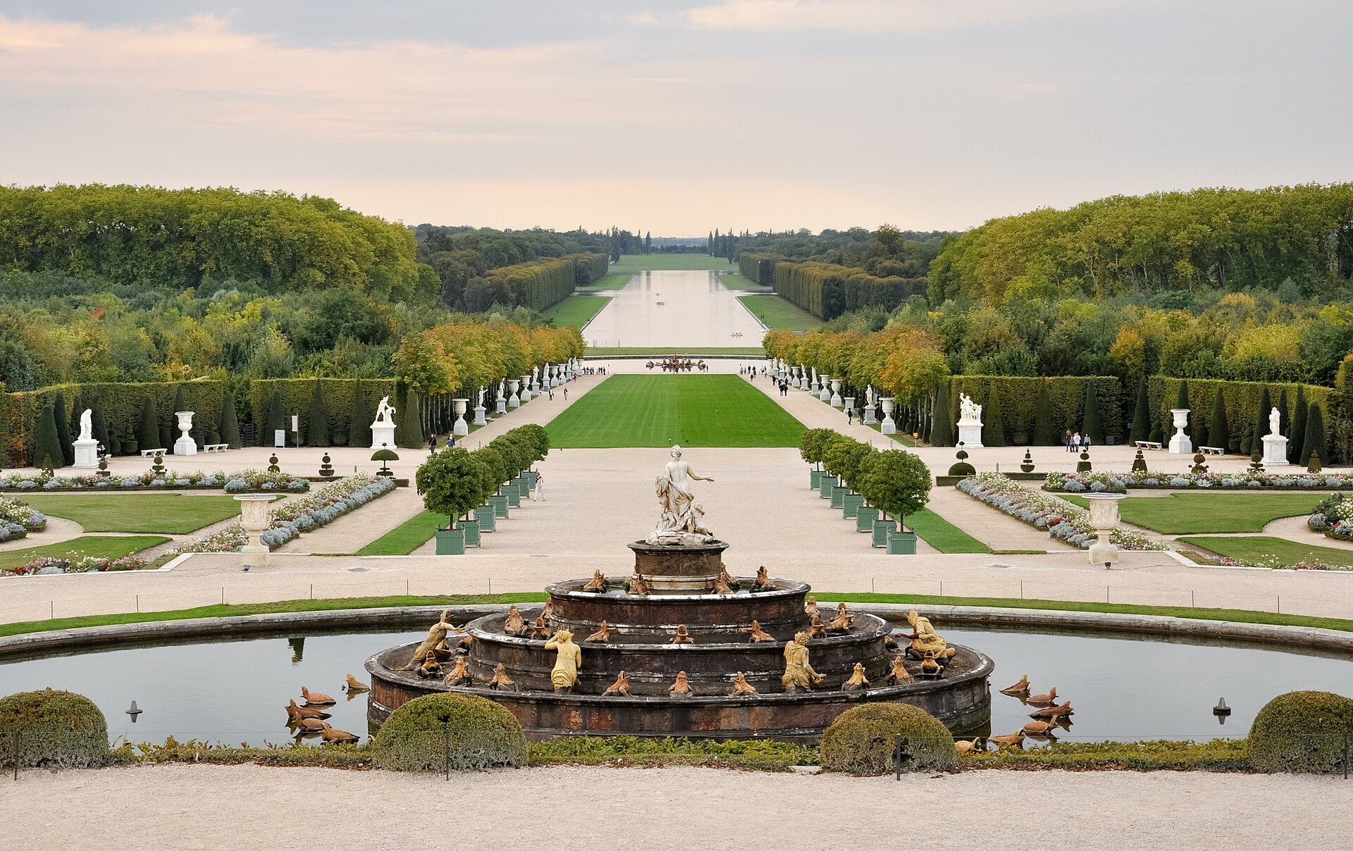 The formal gardens of Versailles seen from the Parterre d'eau, with clipped hedges and paths running away from the palace towards the horizon.